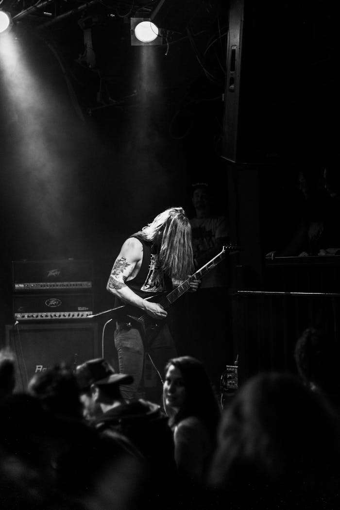 Guitarist with long hair performs live on stage during a metal concert, captivating the audience.