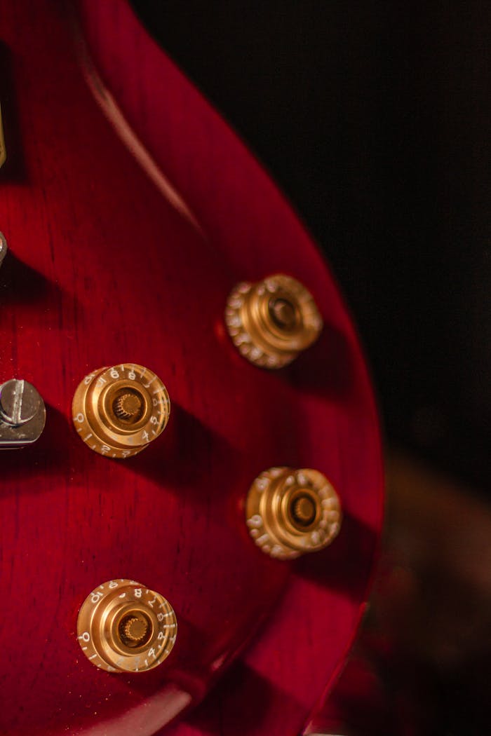 Detailed close-up of golden knobs on a red electric guitar, highlighting musical instrument design.