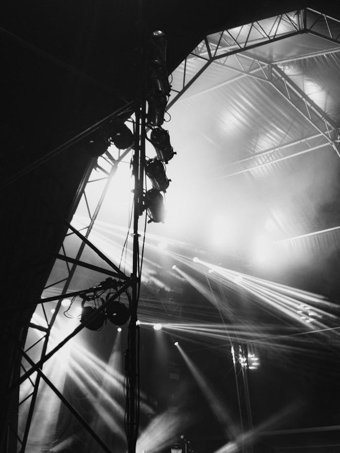 Monochrome image of a concert stage with dramatic lighting and structure.